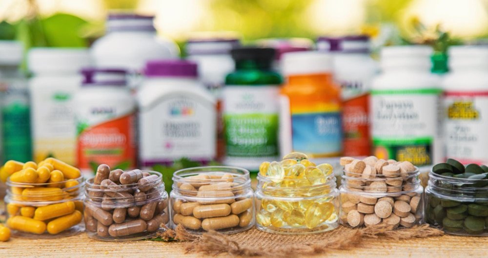 A person comparing supplement bottles and prescription pill containers on a table, symbolizing informed health choices